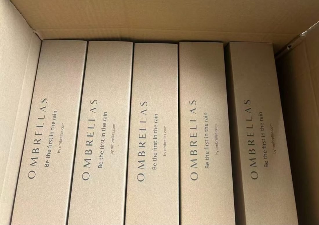 An opened shipping carton showing OMBRELLAS kraft retail boxes standing inside